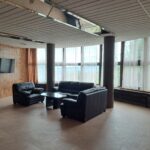 hotelová recepcia zariadenia SUZA - pohľad na lobby bar s kreslami, stolíkom, TV a krásnym výhľadom z veľkých okien